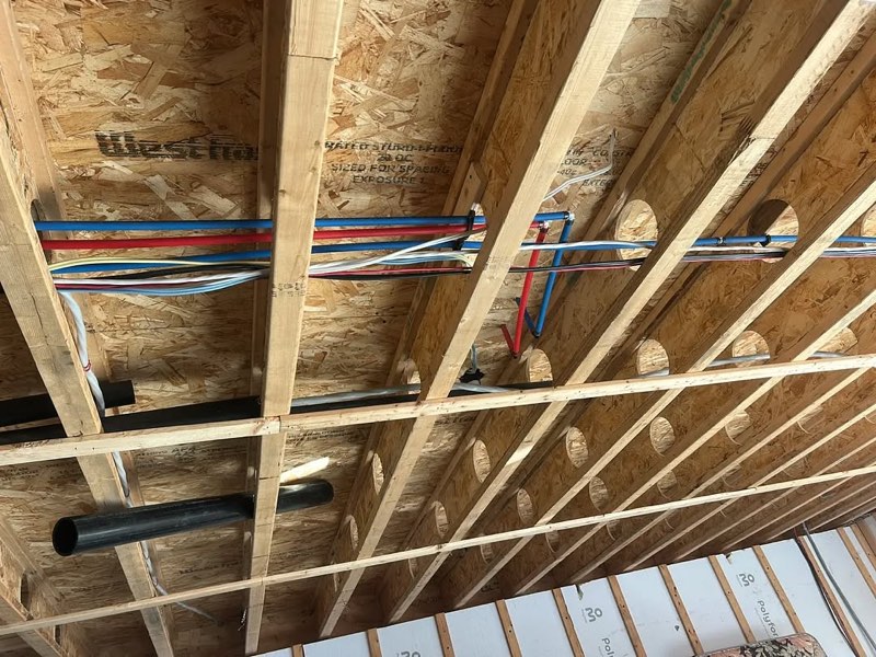 Tuyauterie PEX rouge et bleue sous les solives d’une maison neuve